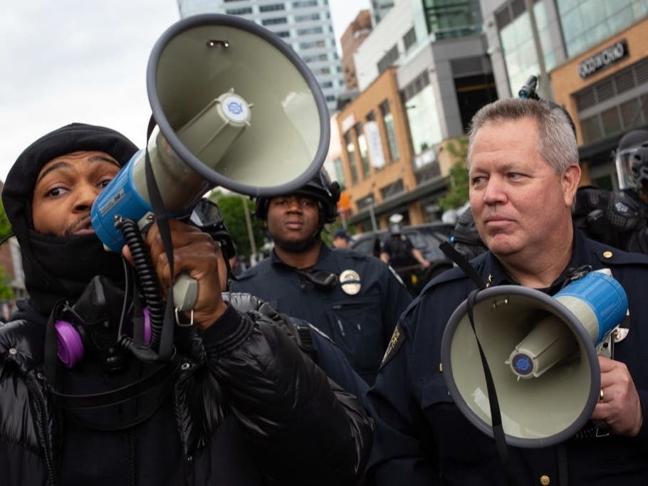 A demonstrator wields a megaphone next to Bellevue Police Chief Steve Mylett as they speak during a racial justice protest on May 31, 2020, in Bellevue, Wash.