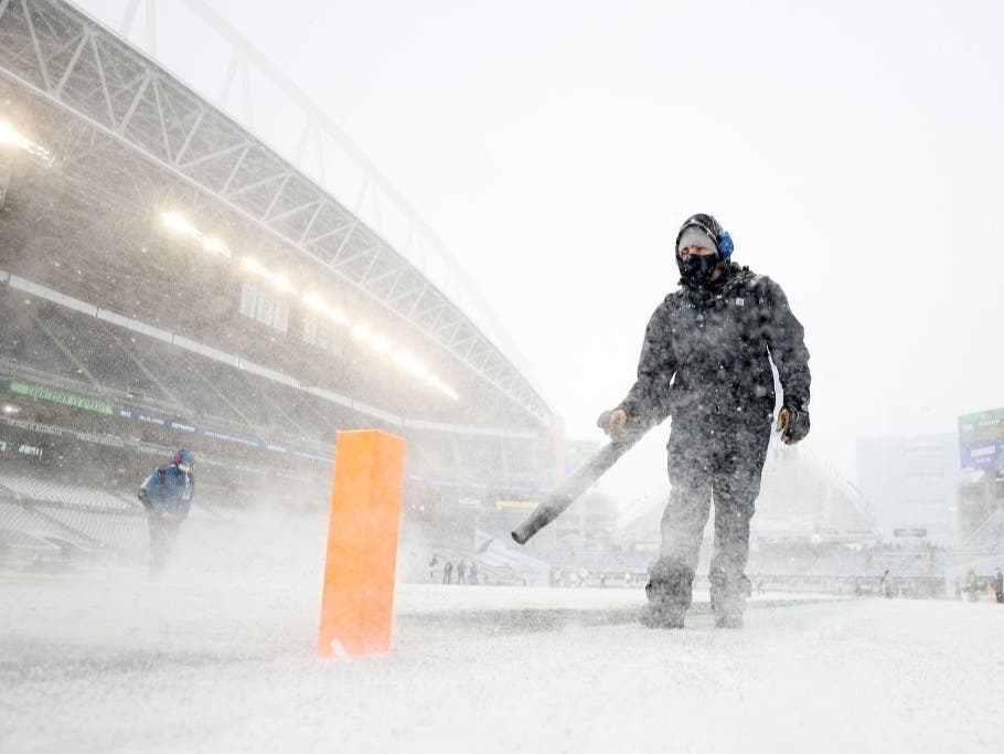 Field staff work on clearing the snow at Lumen Field before the game between the Seattle Seahawks and Chicago Bears on Dec. 26, 2021, in Seattle