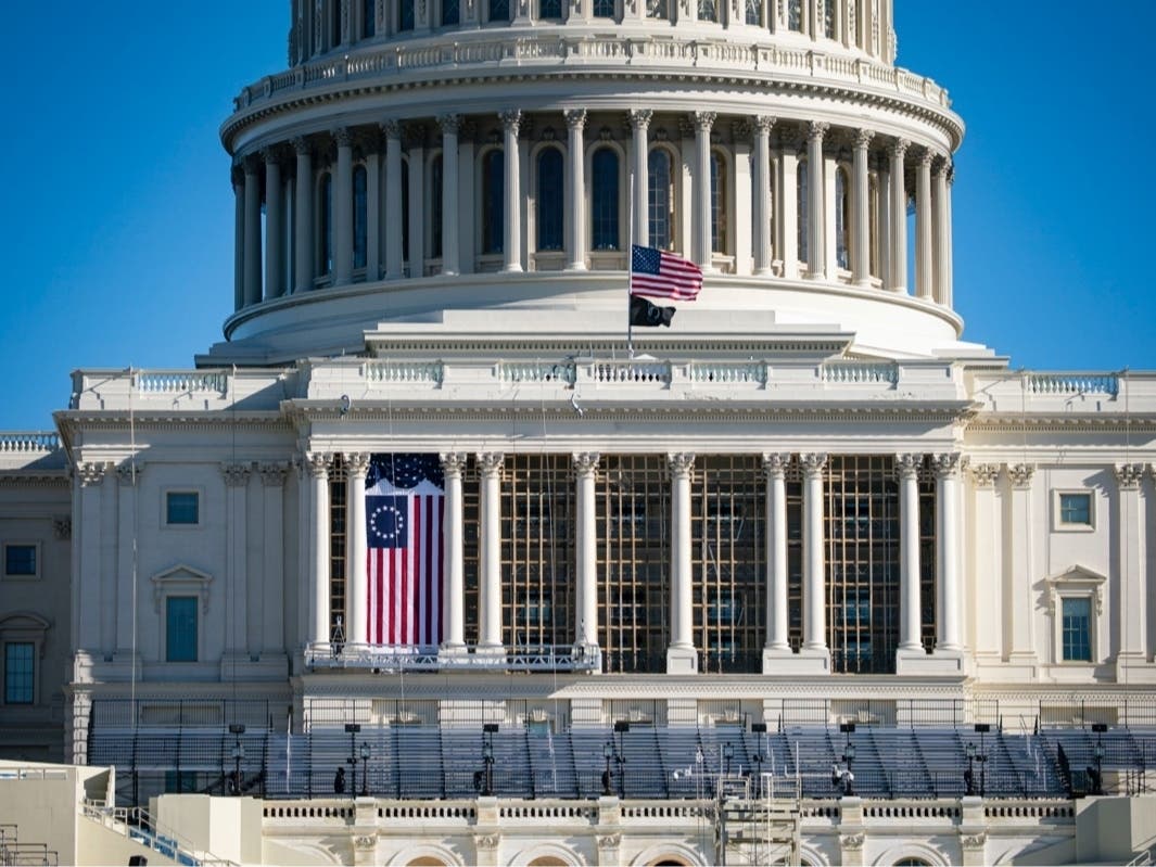 The American flag flies at half-staff as inauguration construction continues on the West Front of the U.S. Capitol on Saturday in Washington, D.C.