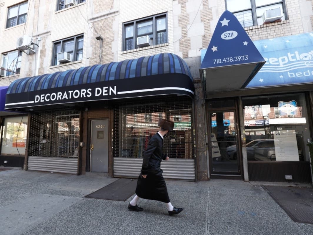A man walks past a closed business in Borough Park, which is largely covered by a state-imposed “red zone” order closing schools and non-essential businesses.