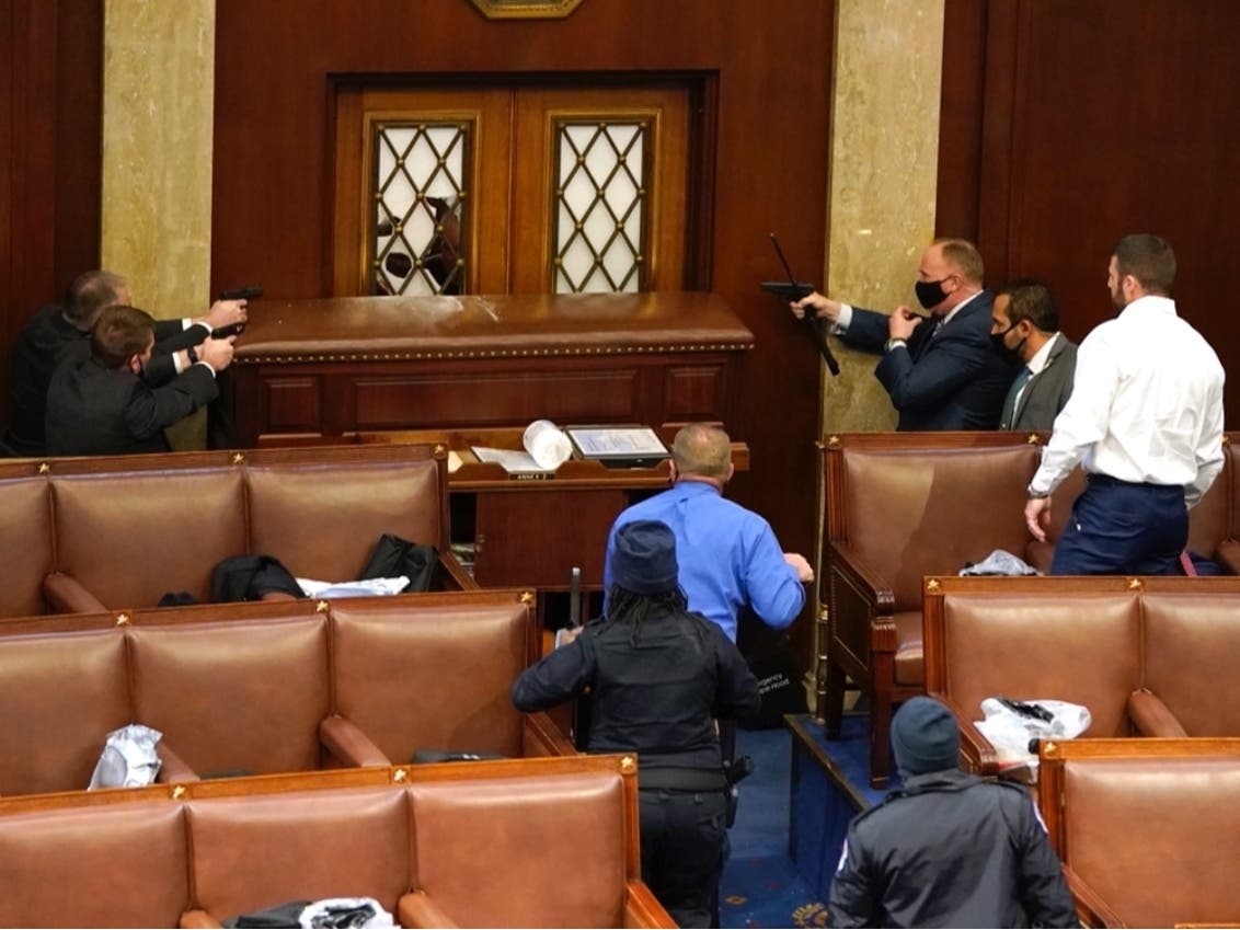 U.S. Capitol police officers point their guns at a door that was vandalized in the House Chamber during a joint session of Congress on Wednesday.