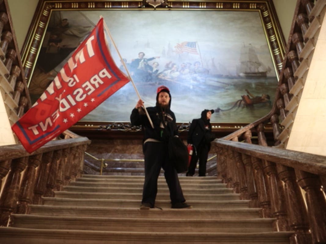 A member of a pro-Trump mob holds a Trump flag inside the US Capitol Building near the Senate Chamber on Jan. 6.