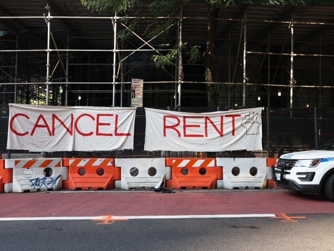 A NYPD vehicle parks in front of a "Cancel Rent" banner hung up by participants of a 'Resist Evictions' rally to protest evictions on Aug. 10.