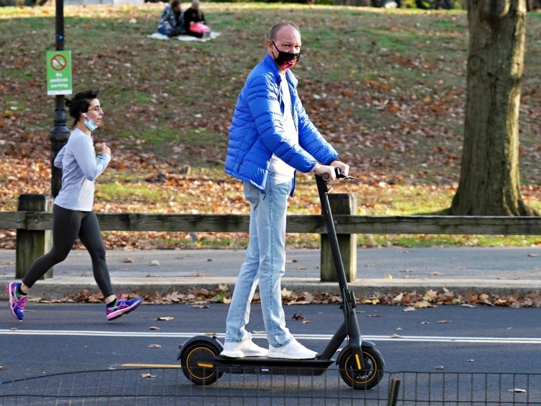 A man wearing a protective mask rides a scooter in Central Park on Nov. 16. 