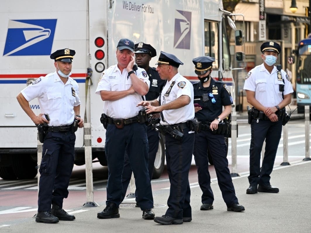 A United States Postal Service truck drives by as NYPD officers gather at Union Square Park as the city continues Phase 4 of re-opening following restrictions imposed to slow the spread of coronavirus on Aug. 25.