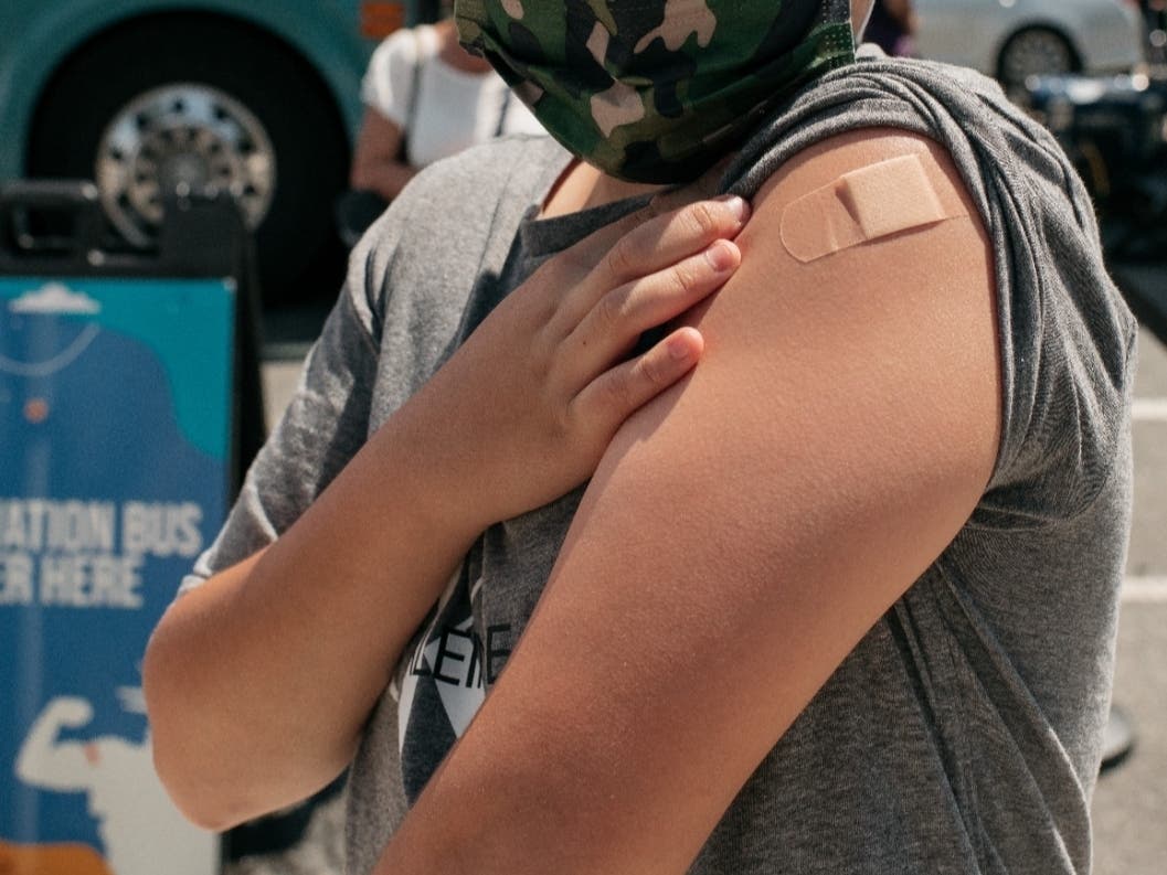 A 13-year-old newly vaccinated against COVID-19 shows his bandage at a pop-up vaccination site on June 5 in Jackson Heights.