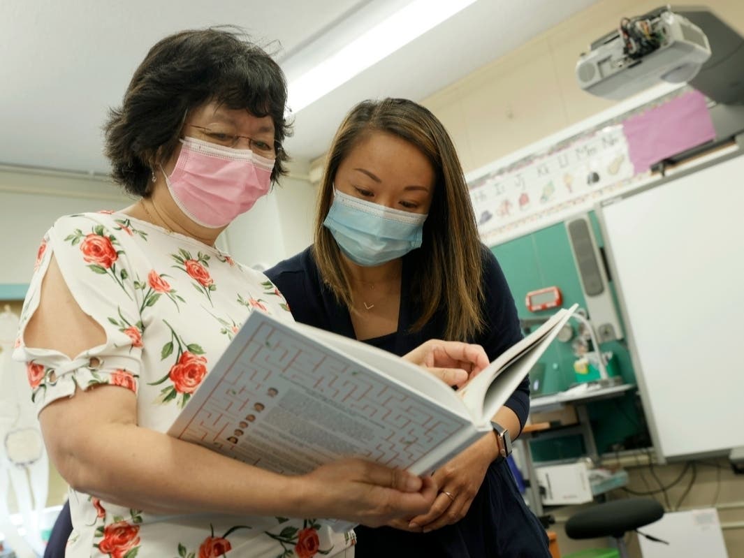 Principal Alice Hom and teacher Laura Lai look over the recently arrived Class of 2021 yearbook at Yung Wing School P.S. 124 on July 22.