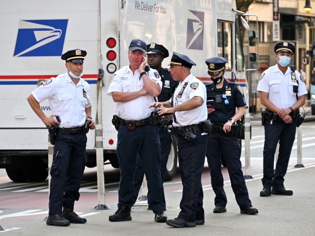 A United States Postal Service truck drives by as NYPD officers gather at Union Square Park as the city continues Phase 4 of re-opening following restrictions imposed to slow the spread of coronavirus on Aug. 25, 2020.