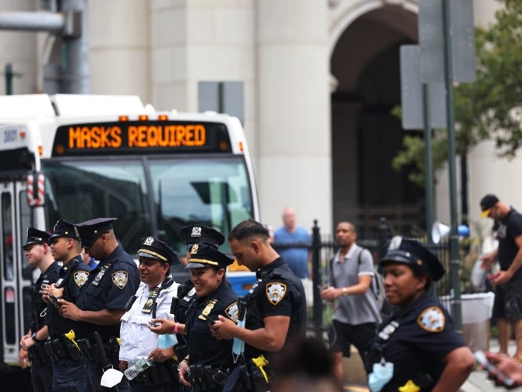 NYPD officers stand watch as people gather at City Hall to protest vaccine mandates on Aug. 9.