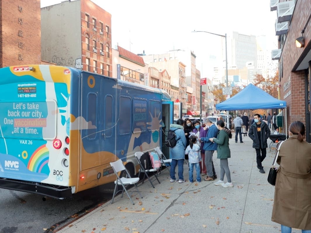 Principal Alice Hom, in purple jacket, stands outside Yung Wing School P.S. 124 and a vax van where for the second time this month, pop-up sites have been stationed to offer students age 5-11 the covid vaccine on Thursday.