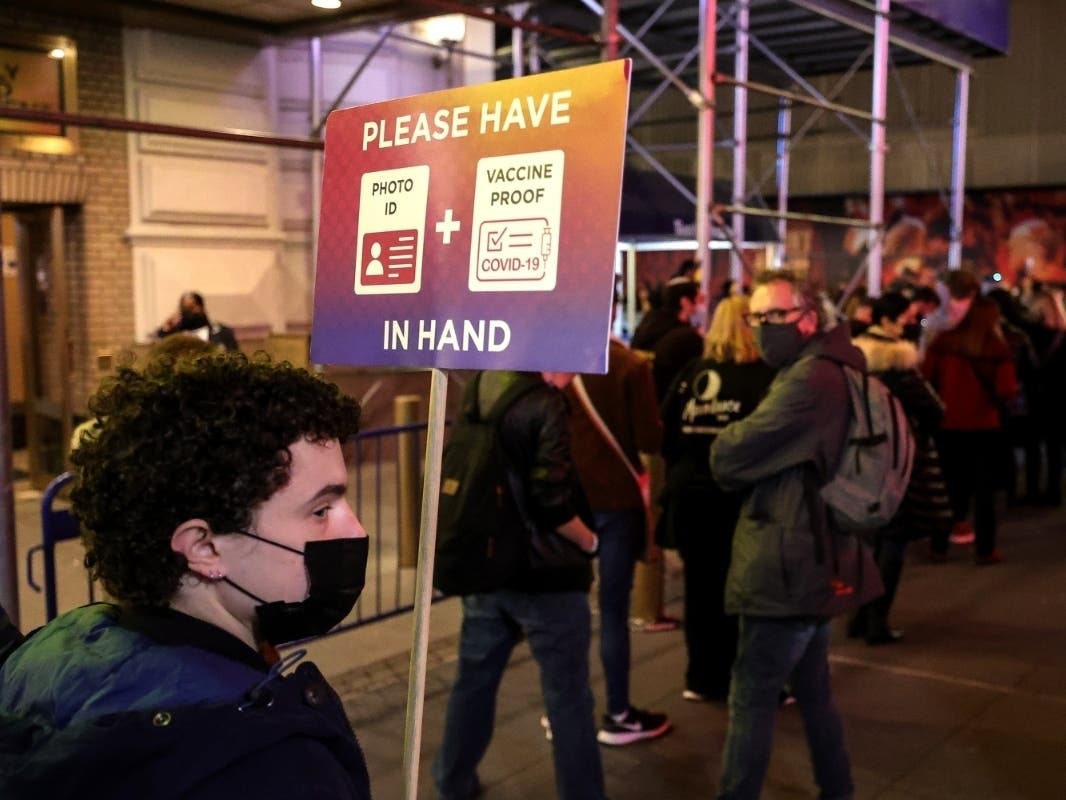 A worker holds a COVID protocol sign for guests attending the evening performance of "Freestyle Love Supreme" at the Booth Theatre on Dec. 16.