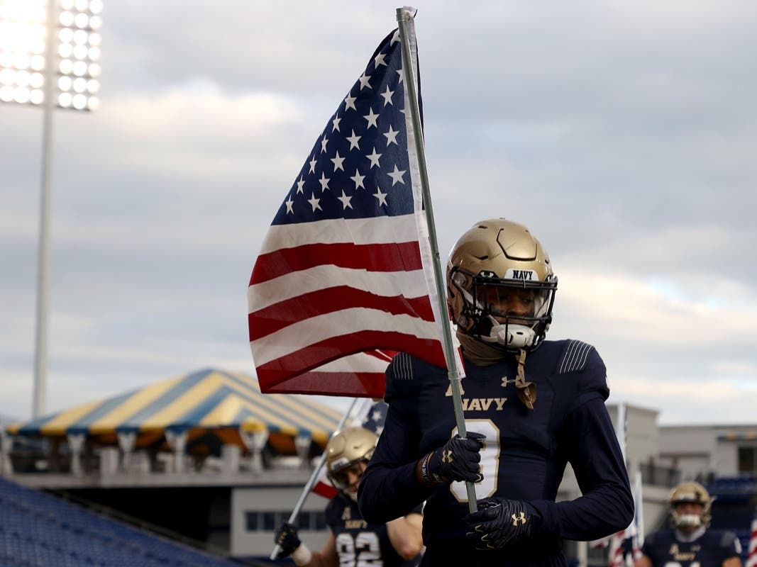 Cameron Kinley carries an American flag as the team takes the field against the Tulsa Golden Hurricane at Navy-Marine Corps Memorial Stadium in December. 