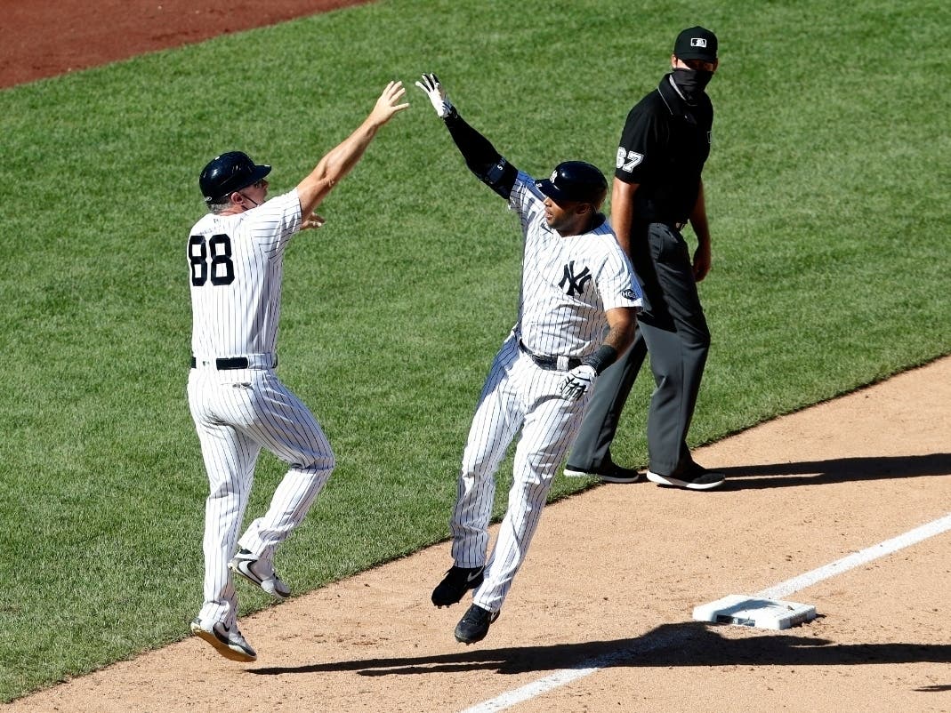 Aaron Hicks #31 of the New York Yankees celebrates his seventh inning game tying two run home run during the first game of a doubleheader against the New York Mets with third base coach Phil Nevin #88 at Yankee Stadium on August 30, 2020 in New York City.