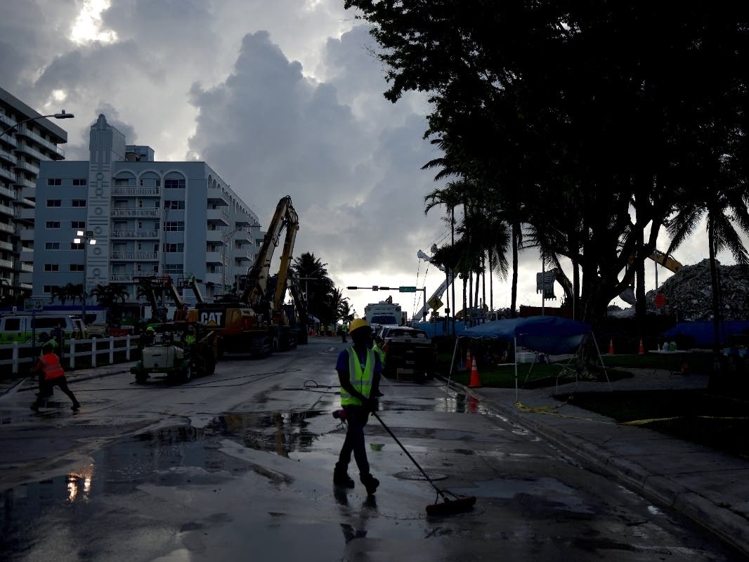 Workers clean the street near the site of the collapsed 12-story Champlain Towers South condo building on July 11, 2021 in Surfside, Florida.