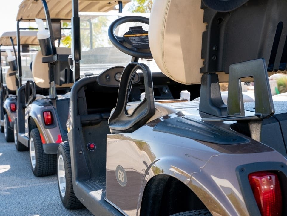 Background image of multiple golf carts parked in order.
