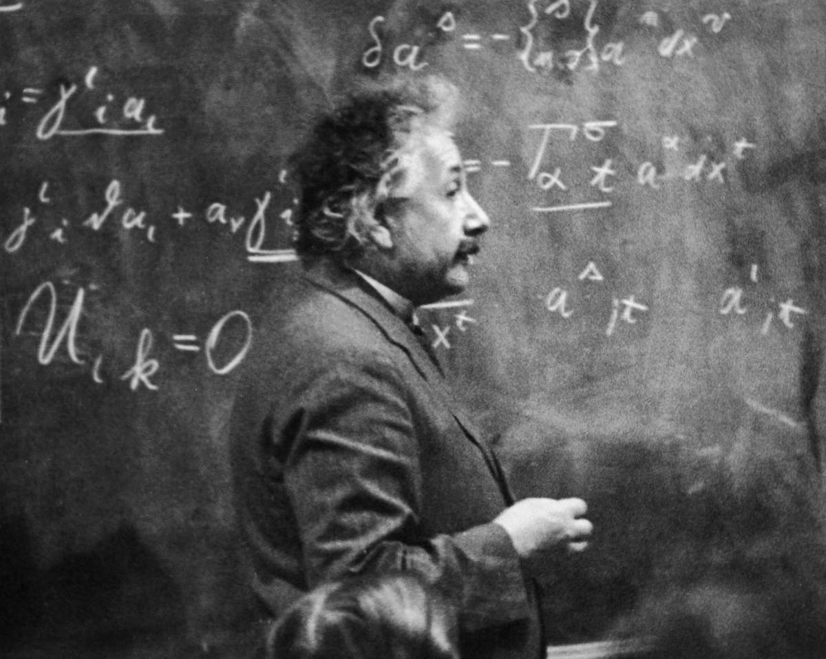 circa 1931: German-born physicist Albert Einstein (1879 - 1955) standing beside a blackboard with chalk-marked mathematical calculations written across it. 