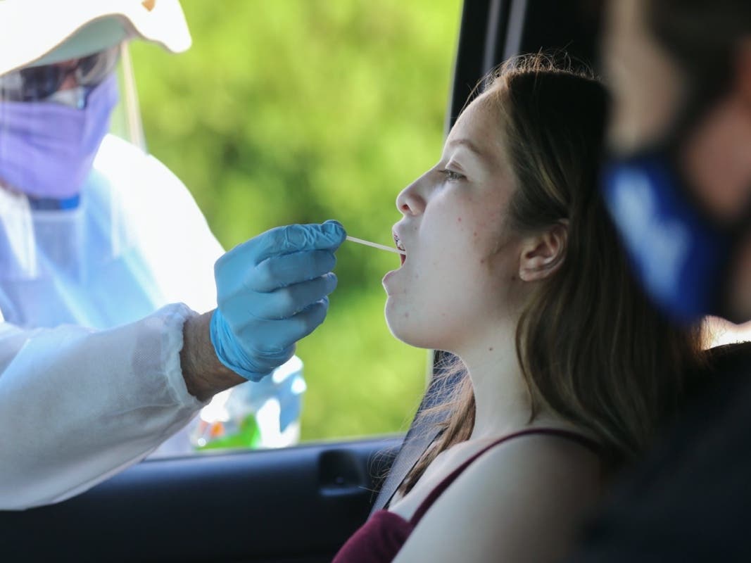 A healthcare worker gives a girl a throat swab test at a drive-in coronavirus testing center at M.T.O. Shahmaghsoudi School of Islamic Sufism on August 11, 2020 in Los Angeles, California. 