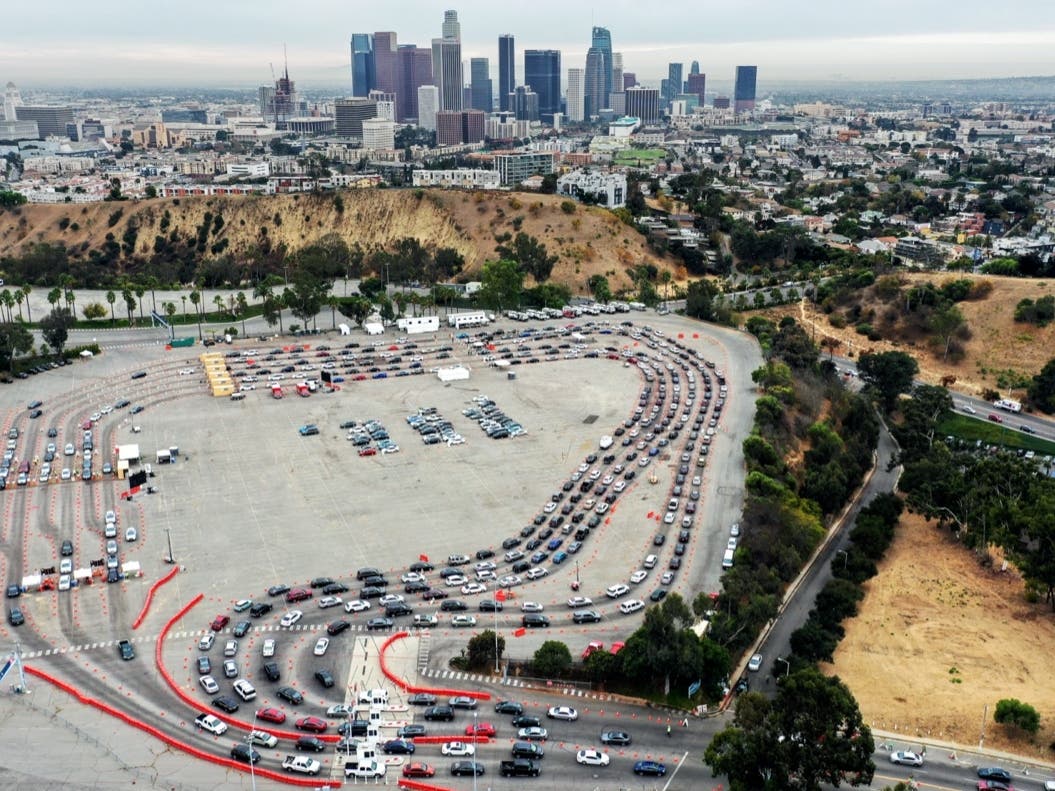LOS ANGELES, CALIFORNIA - DECEMBER 07: In an aerial view from a drone, vehicles line up to enter a COVID-19 testing site at Dodger Stadium on the first day of new stay-at-home orders on December 7, 2020 in Los Angeles, California.