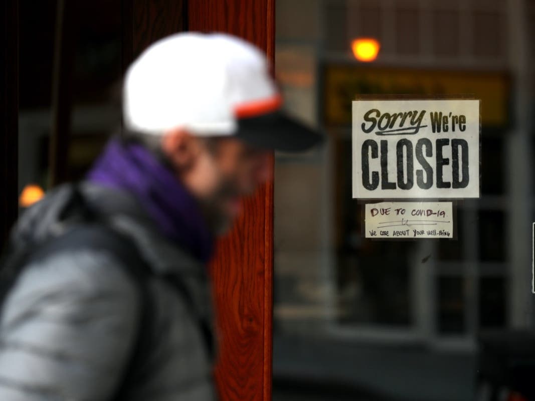 SAN FRANCISCO, CALIFORNIA - MARCH 17: A pedestrian walks by a closed sign on the door of a restaurant on March 17, 2020 in San Francisco, California. 