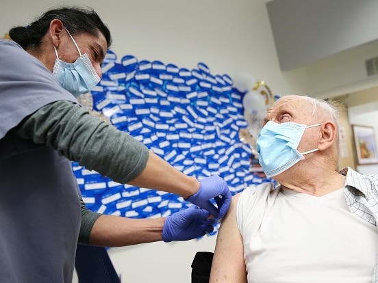 Certified medical assistant Mario Rivera applies a Band-Aid after administering a COVID-19 Pfizer vaccination to Anthony Banash at Harbor-UCLA Medical Center Thursday in Torrance, California.