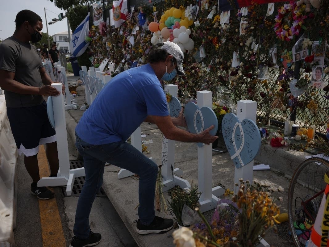 Randy Wagoner, a member of the Holy Cross Lutheran Church, rearranges a line of wooden hearts with new ones, representing the victims of the collapsed 12-story Champlain Towers South condo building, at the memorial site July 13. 