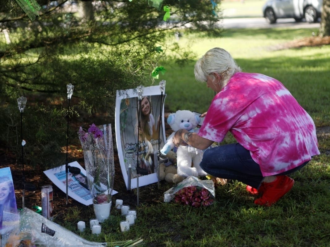 A woman leaves an item at a makeshift memorial for Gabby Petito in North Port, Florida. The city is removing the memorial and giving the items to her family.