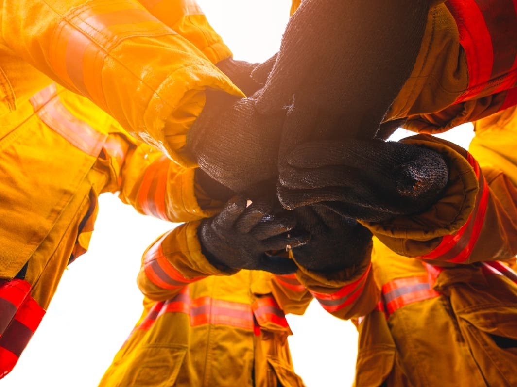 A file photo of firefighters putting their hands up.