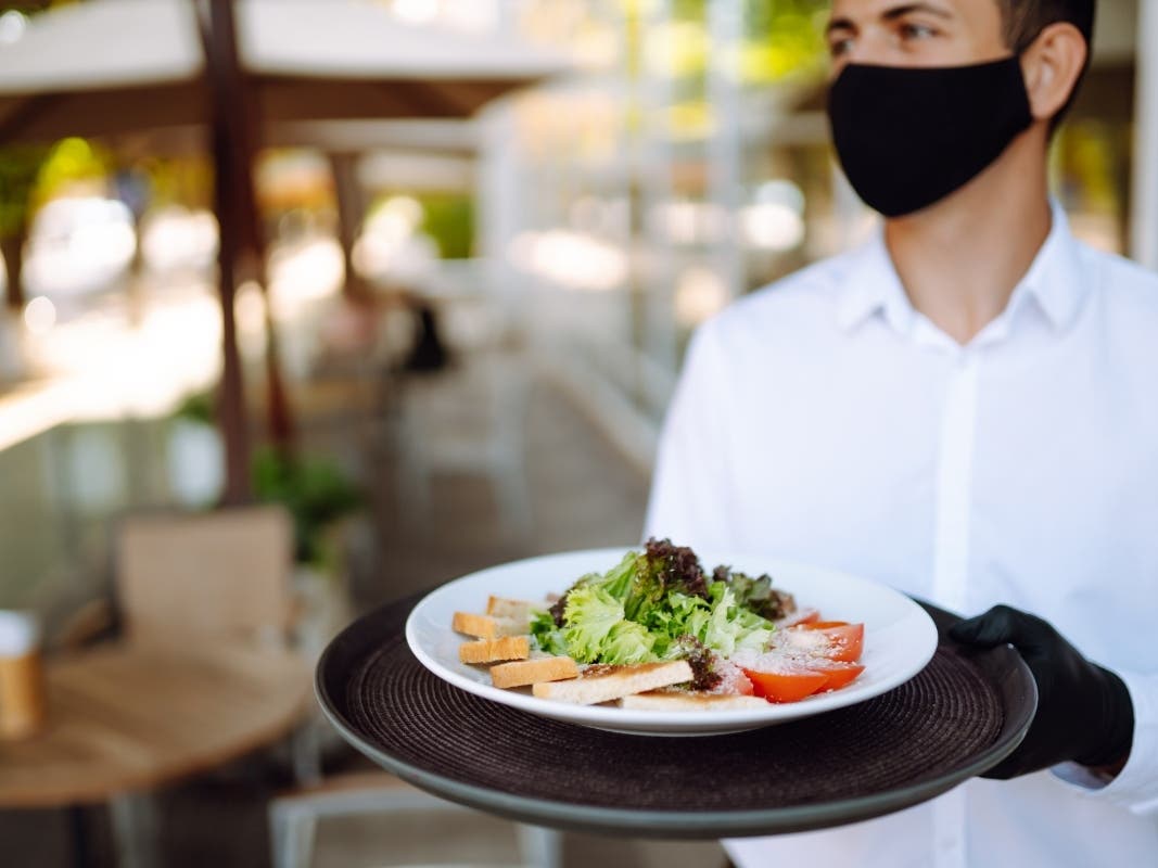 A file photo of a young waiter wearing protective face mask while working in a reopened cafe after the coronavirus epidemic.