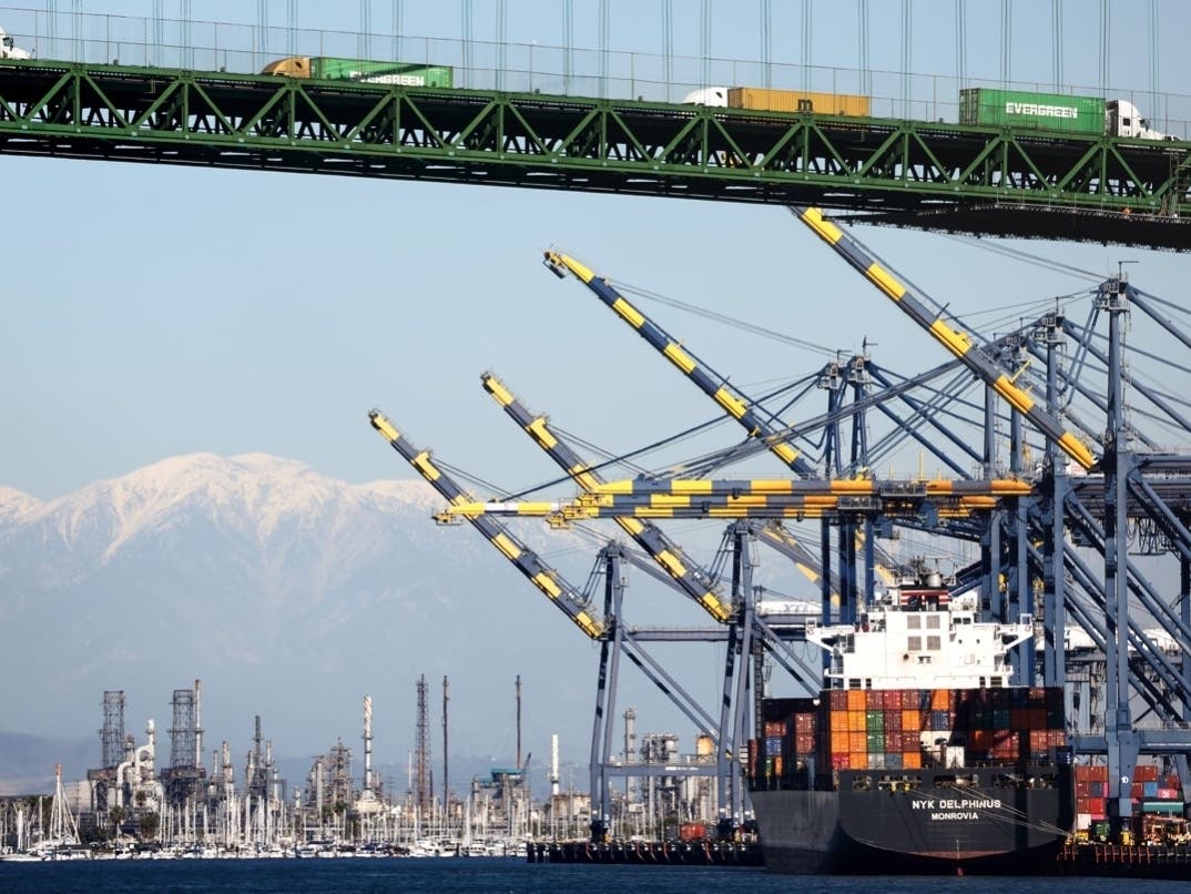 Shipping containers are stacked on a container ship at the Port of Los Angeles, as trucks pass above in front of the snow-capped San Gabriel Mountains, on February 7, 2023 in Los Angeles, California. 