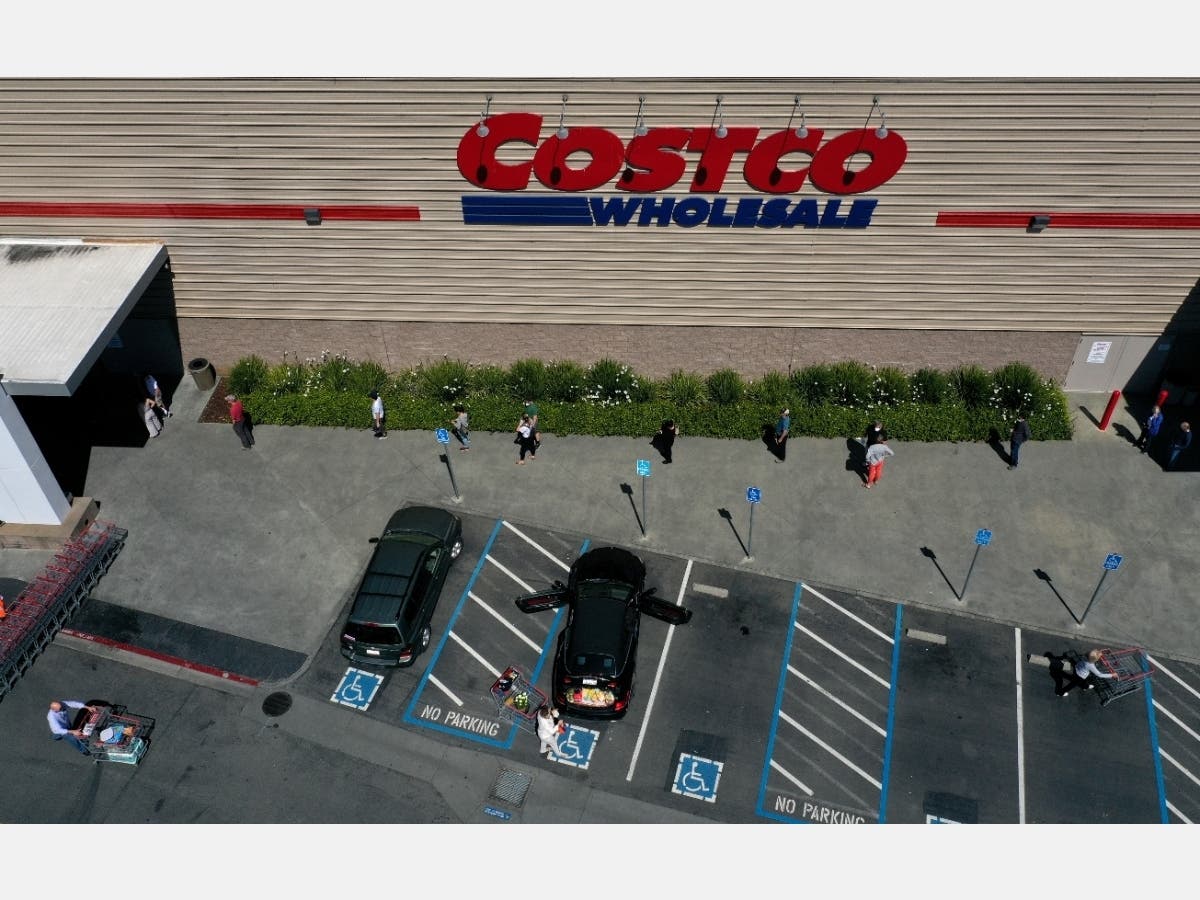 In this aerial view from a drone, shoppers practice social distancing waiting in line to enter a Costco store on April 13, 2020 in Novato, California.