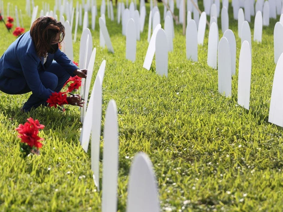 North Miami Councilwoman Mary Estime-Irvin writes the name of a friend lost to Covid-19 onto a tombstone set up during an unveiling of a memorial for local lives lost at Griffing Park.
