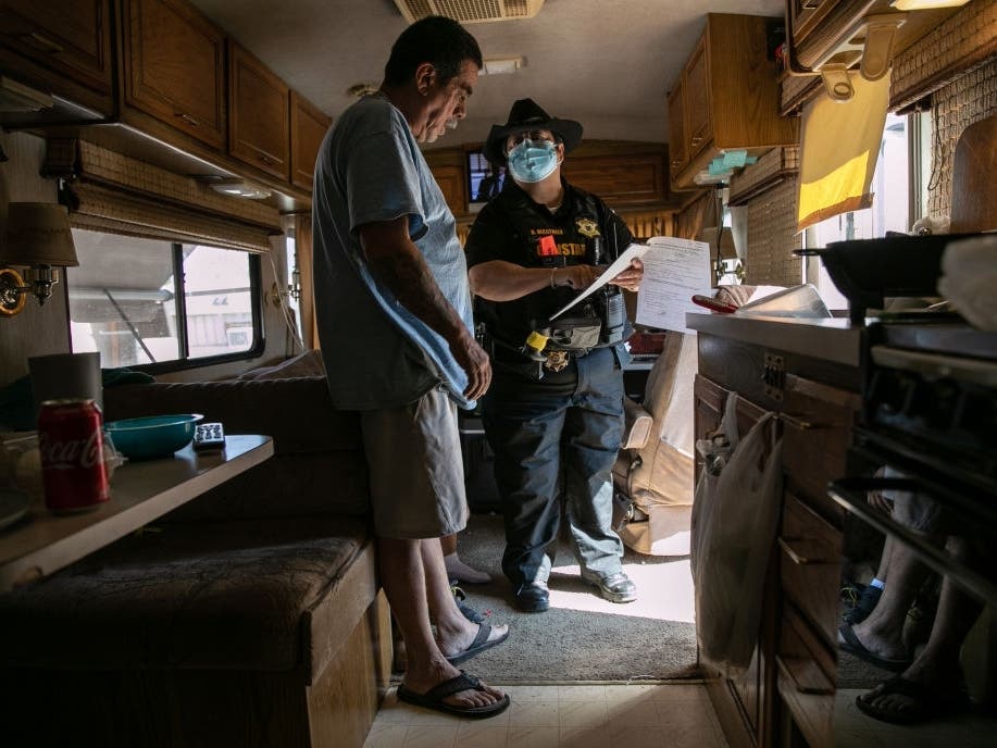 Maricopa County constable Darlene Martinez shows Hector Medrano court documents ordering his family's eviction from an RV park on Oct. 7 in Phoenix, Arizona.