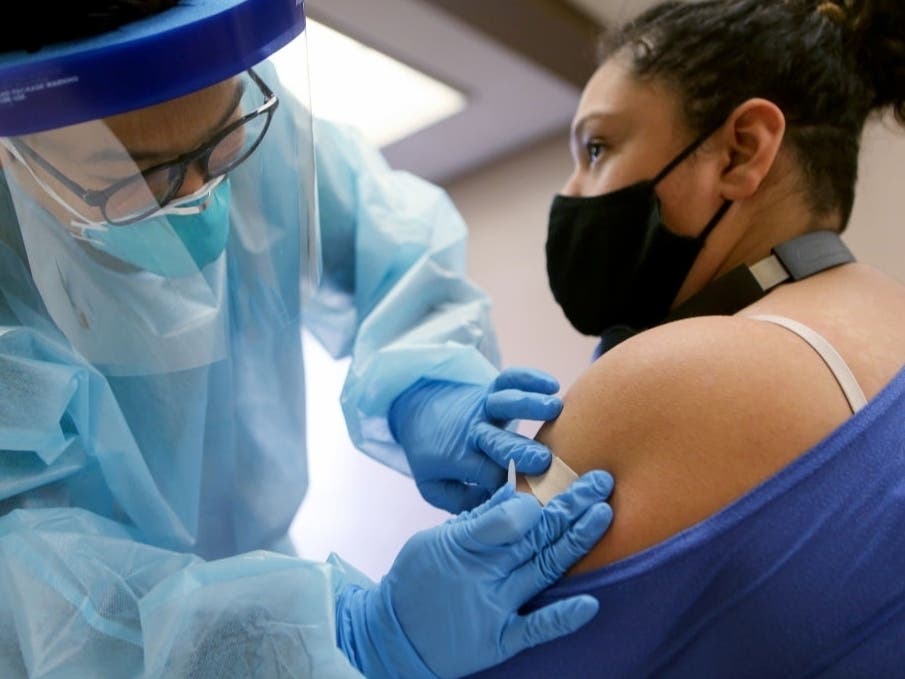 A nurse applies a band- aid after administering the flu vaccination shot to a woman at a free clinic held at a local library on Oct. 14, 2020, in Lakewood, California. 