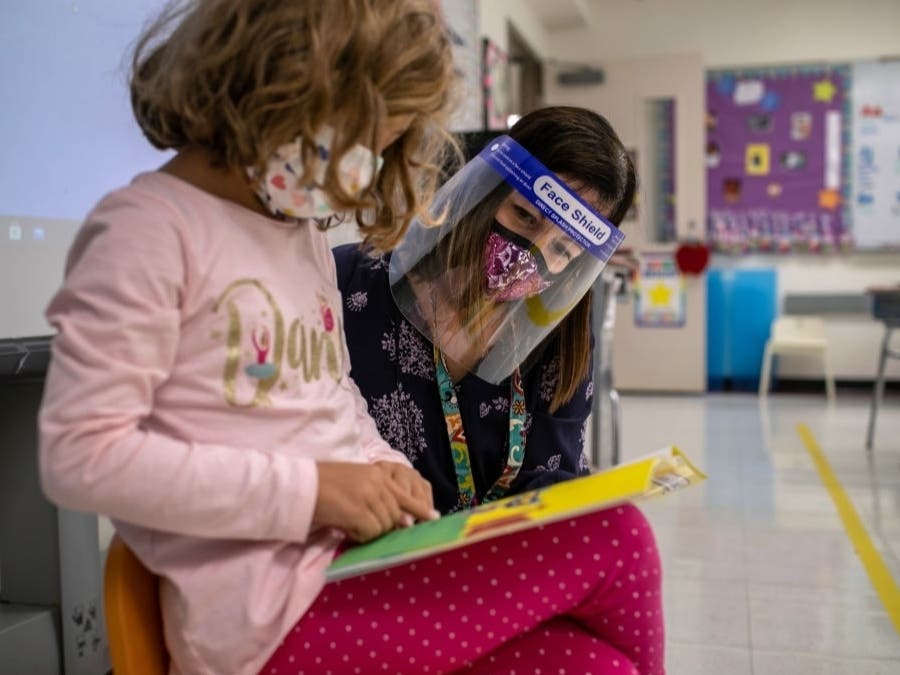 Teacher Elizabeth DeSantis listens as a first grader reads during class at Stark Elementary School in Stamford, Connecticut. Teacher morale has crashed over the course of the pandemic. While some teachers are hanging out, others are choosing to leave.