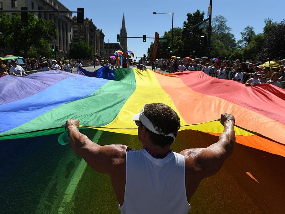 Mark Kraft holds onto a large Rainbow flag as he marches down Colfax Avenue while taking part in the annual Denver PrideFest parade.