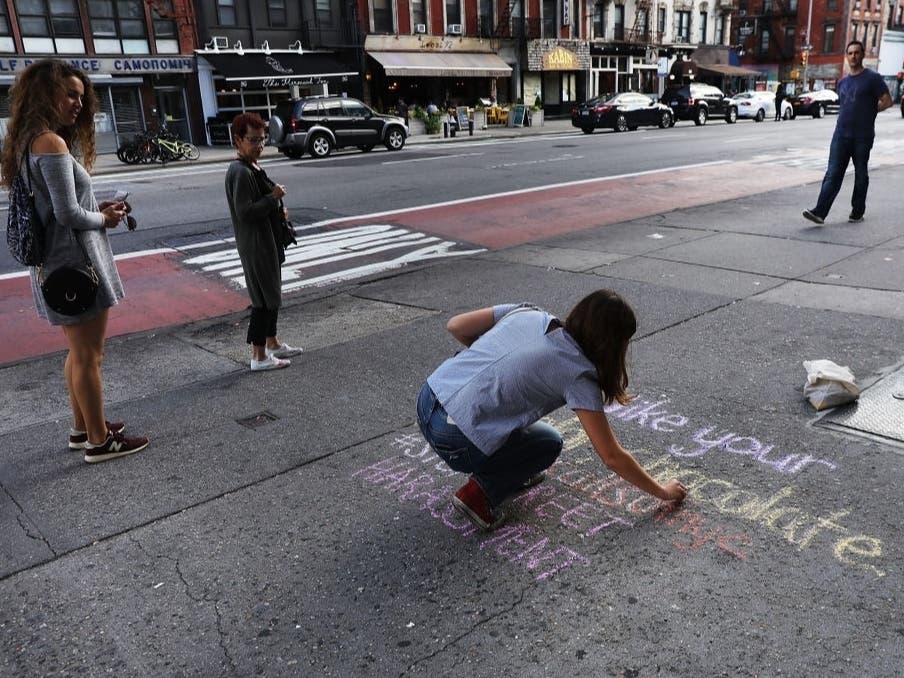 Sophie Sandberg uses colored chalk to draw a quote on the sidewalk from a catcall made towards a woman on Oct. 3, 2018, in New York City. 