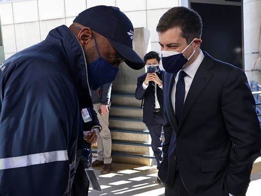 U.S. Secretary of Transportation Pete Buttigieg, right, wearing two masks, speaks with an Amtrak employee during a visit to Union Station Feb. 5 in Washington, D.C.