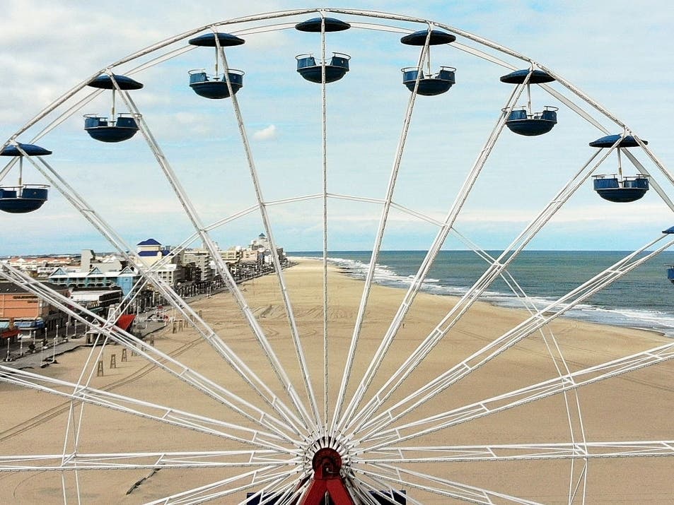 An aerial view from a drone shows an empty beach through a ferris wheel on April 27 in Ocean City, Maryland. The beach and boardwalk were closed because of the coronavirus; all hotels, beaches and the boardwalk are now open.