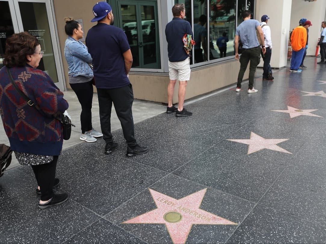 People maintain social distancing while standing in line to enter a Trader Joe's, along the Hollywood Walk of Fame, as the coronavirus pandemic continues on March 25, 2020 in Los Angeles, California.