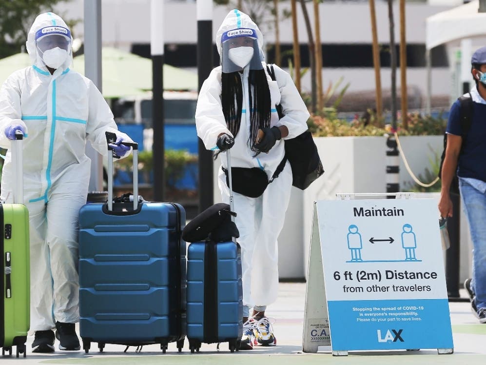 Air travelers arriving from New York in personal protective equipment (PPE) walk on their way to board a Lyft vehicle at Los Angeles International Airport (LAX) amid the COVID-19 pandemic on August 20, 2020 in Los Angeles, California. 