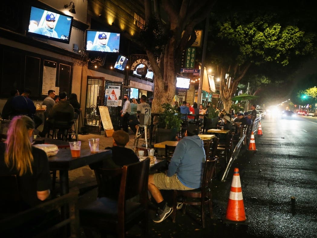People view a television broadcast of Game 1 of the 2020 World Series between the Los Angeles Dodgers and the Tampa Bay Rays at an outdoor bar and restaurant, with seating on the street due to COVID-19, on October 20, 2020 in Los Angeles, California