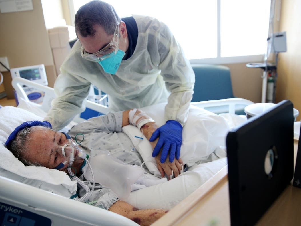 Chaplain Kevin Deegan prays with COVID-19 patient Esperanza Salazar, as she speaks with family members remotely, at Providence Holy Cross Medical Center.