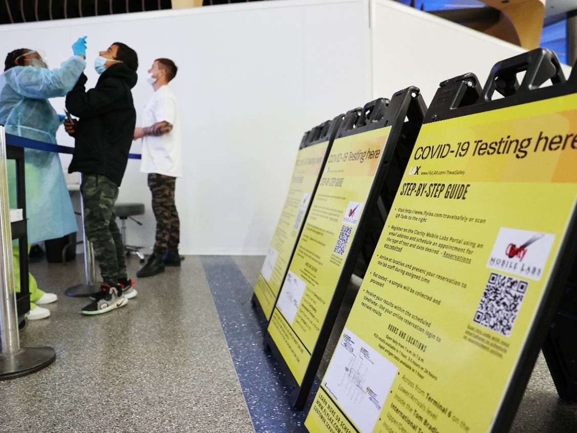 Merline Jimenez (L) administers a COVID-19 nasopharyngeal swab to a person at a testing site located in the international terminal at Los Angeles International Airport (LAX) amid a surge in omicron variant cases on December 21, 2021 in Los Angeles.