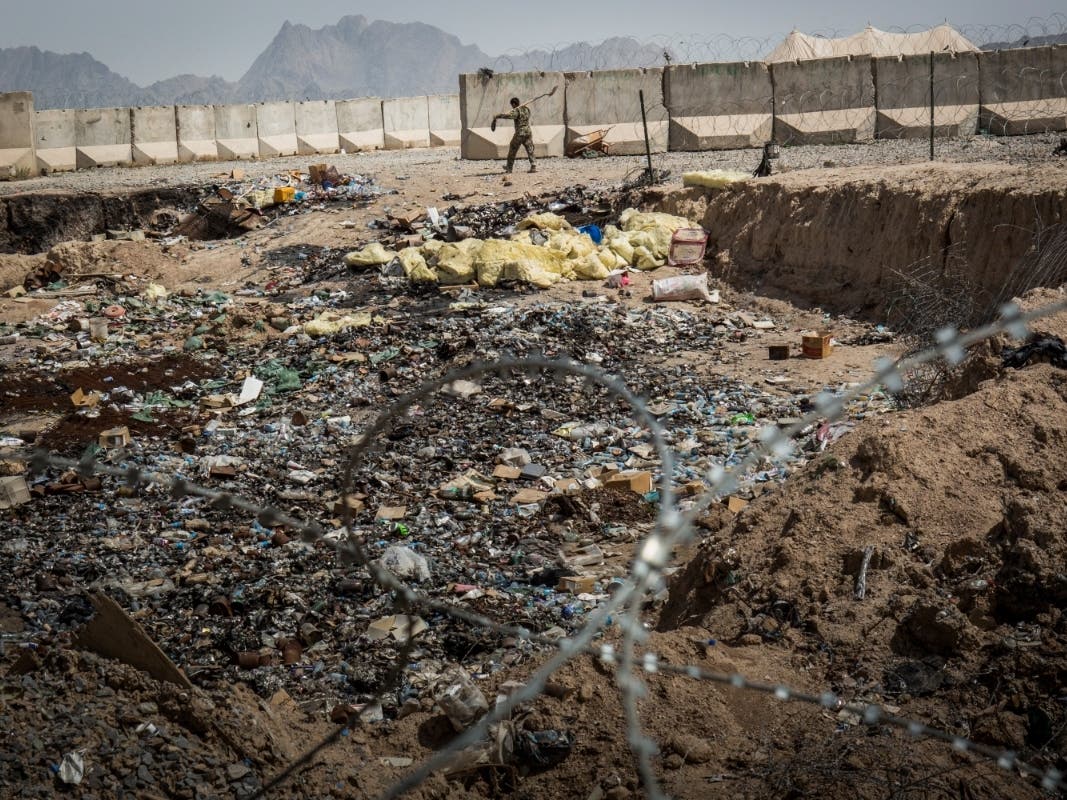 A soldier in the Afghan National Army walks past a burn pit at a command outpost handed over from the United States Army on March 22, 2013 in Kandahar Province, Zhari District, Afghanistan.