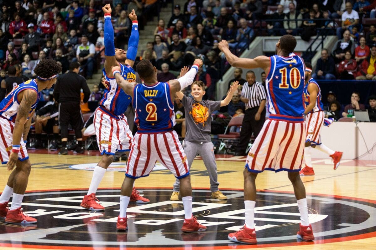 Harlem Globetrotters have some fun with a fan on the court.