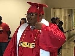 A Kennedy School graduate proudly walks down the aisle to receive his diploma. 