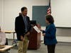 Dr. Tris Carta, President of the Manchester Road Race Committee (left), speaks with Mary Jane Foster, chief executive officer of Hartford Interval House, during ceremonies at the Manchester Police Department headquarters.