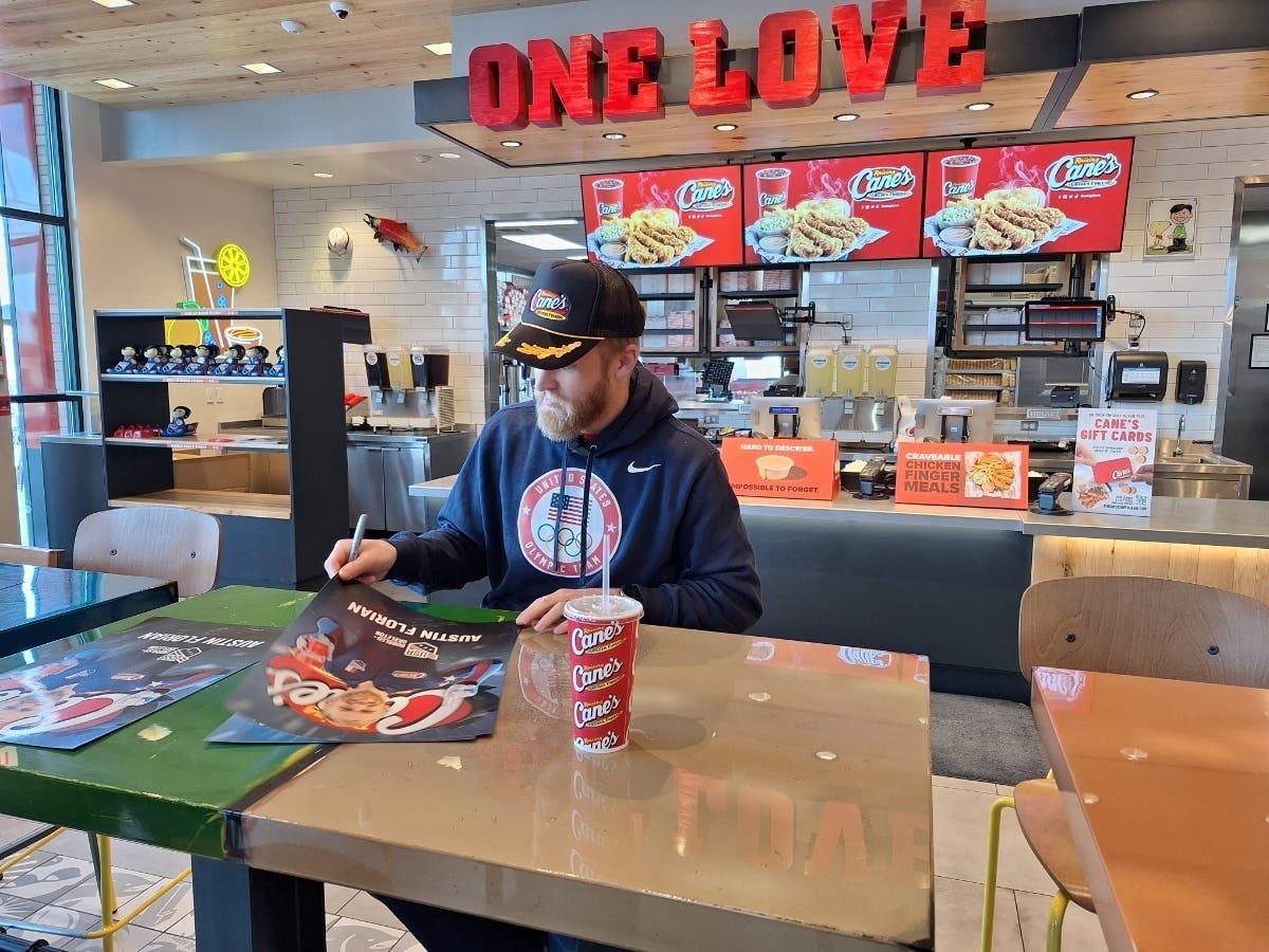 U.S. skeleton athlete Austin Florian signs posters at Raising Cane's in Manchester Wednesday. 