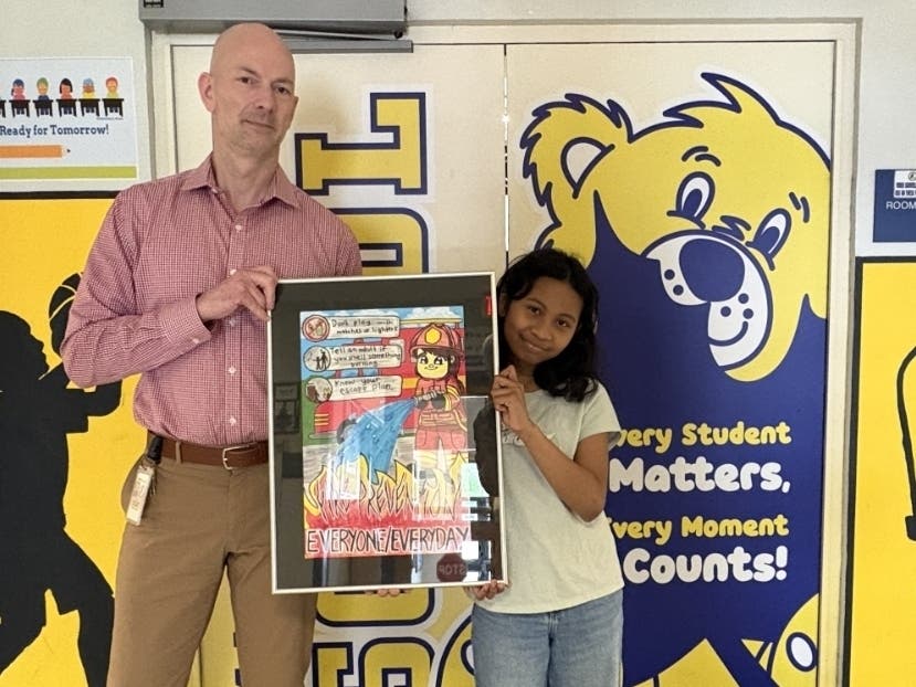Jamie Fernandez and Maple Street School Principal Josh Egan pose with the winning poster. 