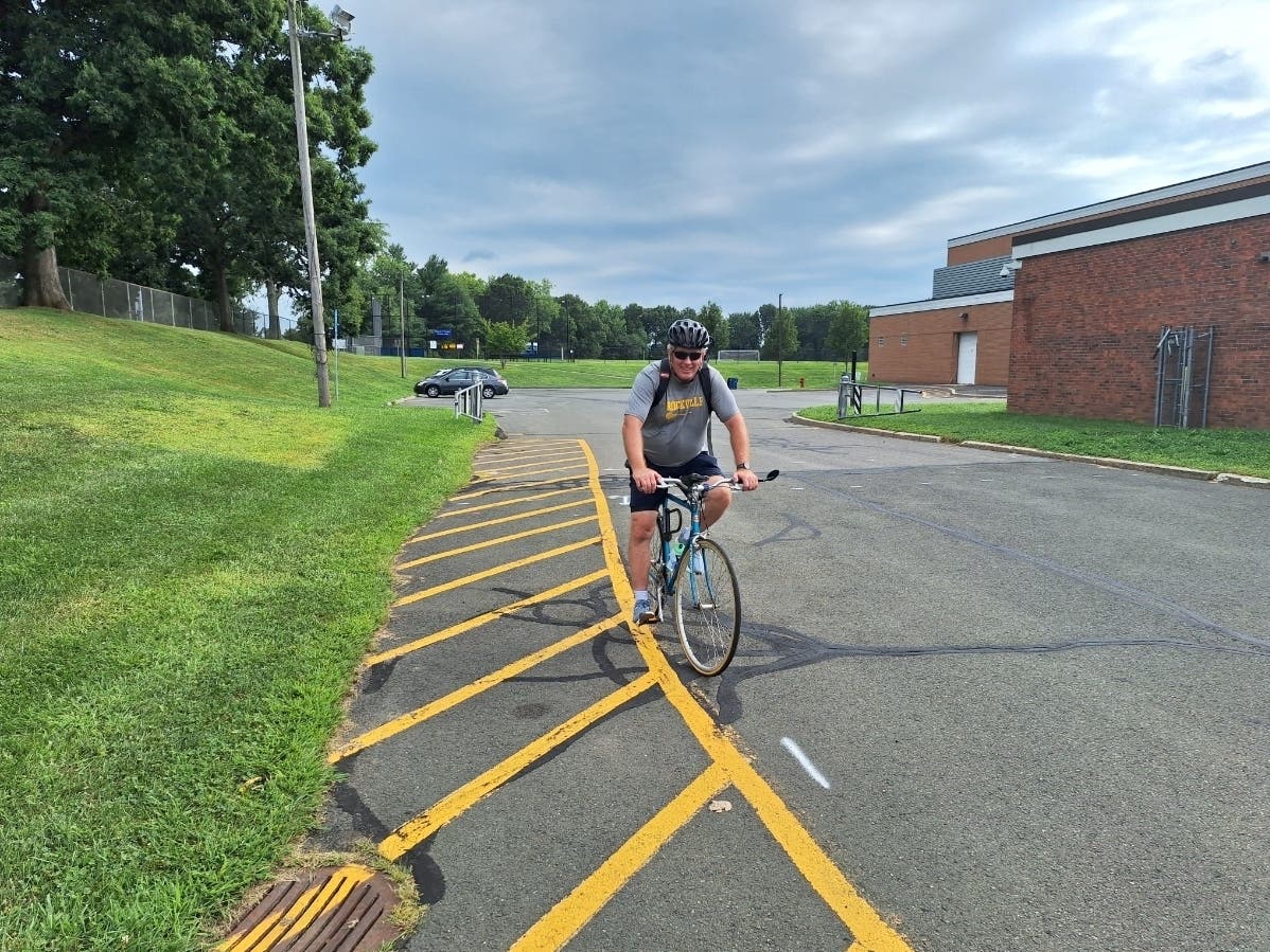 RHS girls lacrosse coach Friday finishes a tour of the NCCC on a bicycle to fight food insecurity. 